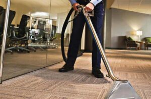 Flooring technician using a hot water extraction wand on office carpet in San Diego