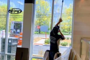 Window cleaner washing storefront glass on a San Diego commercial building